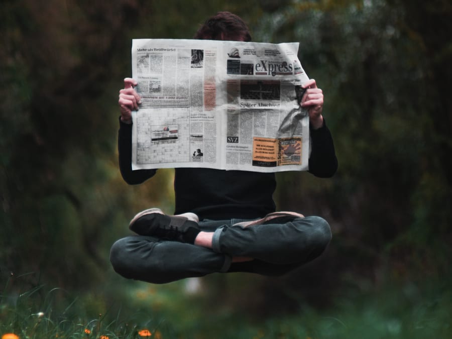 person reading newspaper while levitating