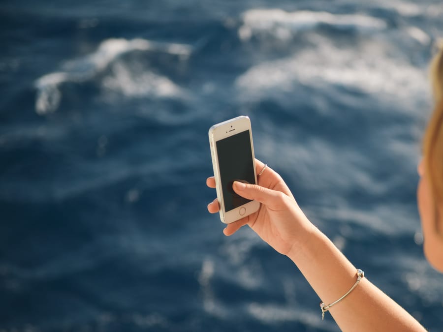Woman Holding Silver Iphone 5s in Black Screen Near Body of Water