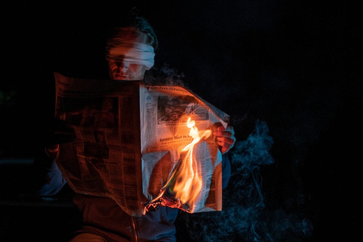man holding burning newspaper